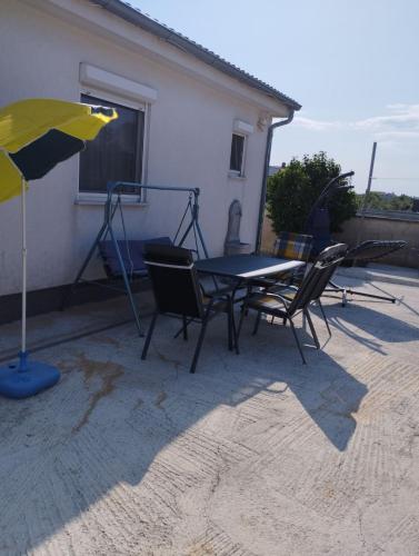 um pátio com uma mesa, cadeiras e um guarda-sol em Apartman Grbić em Vodnjan