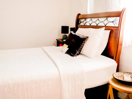 a bedroom with a white bed with a wooden headboard at Casa Perpetua Hotel D Charm in Manaus