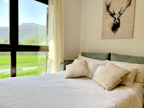 a white bed with two pillows and a window at Apartament de disseny rústic amb vistes by RURAL D'ÀNEU in Esterri d'Àneu