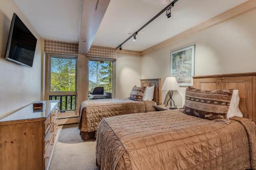 a bedroom with two beds and a tv and windows at Interlude Condominiums 2-Bedroom Unit 202 in Snowmass Village