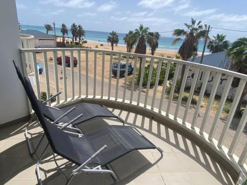 een stoel op een balkon met uitzicht op het strand bij Leme Bedje Sea View Apartments with Pool in Santa Maria