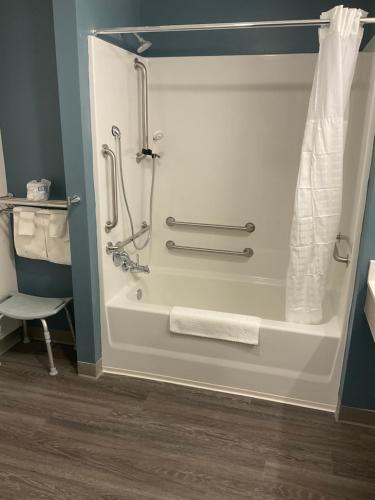 La salle de bains est pourvue d'une douche, de serviettes et d'un lavabo. dans l'établissement WoodSpring Suites Hermitage - Nashville Airport, à Hermitage