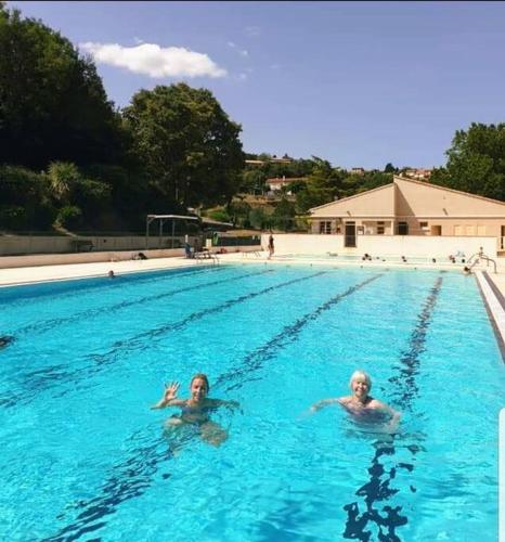 two people are swimming in a swimming pool at Rue Basse - village house overlooking the Pyrenees in Montréal