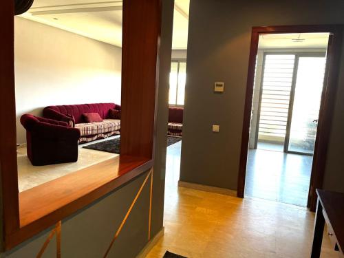 Short Stay Apartment aéroport casablanca في نواصير: غرفة معيشة مع أريكة حمراء ومرآة