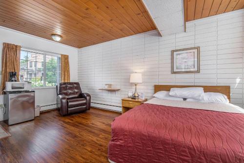 1 dormitorio con 1 cama y 1 silla en The Sierra Motel, en Traverse City