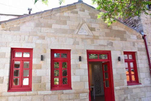 a stone building with red doors and windows at The art studio in Samothráki