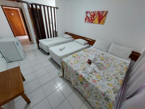 a small room with two beds and a television at Hotel Kalifornia in Porto Seguro