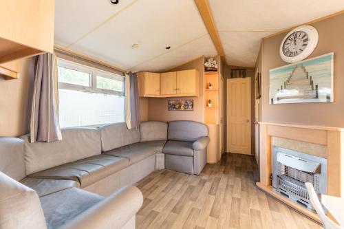 a caravan living room with a couch and a fireplace at Mobil Home Le Berlin in Noyelles-sur-Mer