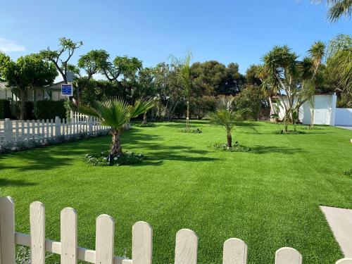 a white fence in front of a yard with palm trees at Camping Riberamar in Oropesa del Mar