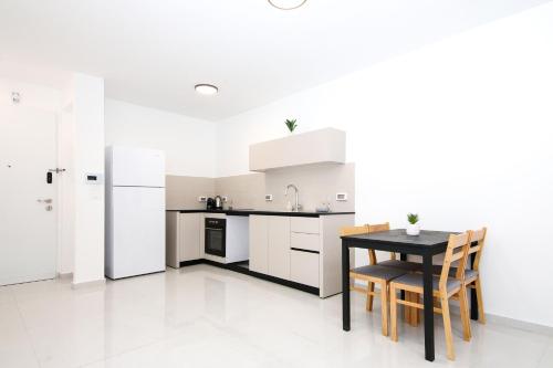 a kitchen with white appliances and a table and chairs at סוויטה אגריפס 8 in Jerusalem