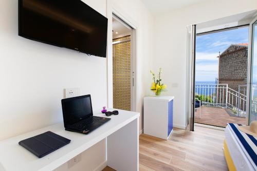 a room with a laptop on a desk with a balcony at YourHome - Relais Loggia Li Galli in Massa Lubrense