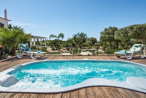 einen Pool auf einer Terrasse mit Stühlen und einem Haus in der Unterkunft VILLA CARACOL Heated Swim Spa & Mini-Golf in Luz de Tavira