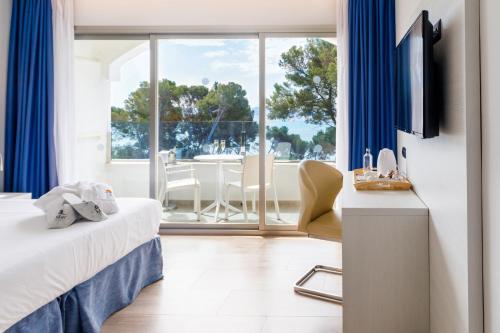 a hotel room with a bed and a large window at Mar Hotels Alcanada in Port d'Alcudia