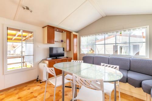 cocina y sala de estar con mesa de cristal y sillas en Mobil Home Le Tokyo, en Noyelles-sur-Mer
