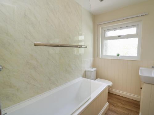 Baño blanco con bañera y lavamanos en Lavender Lodge, en Haverfordwest