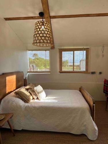a bedroom with a bed in a room with windows at Cosy Cabane Boise solaire, Balneo bath et toilette seche a la Ferme in Mimizan