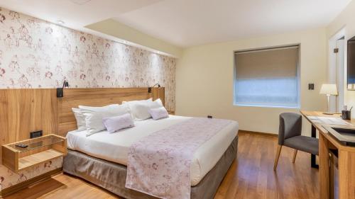 una camera d'albergo con letto e scrivania di Rugendas Hotel Boutique by Time Hotel & Apartments a Santiago