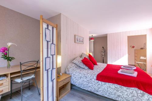 een slaapkamer met een bed met rode kussens en een bureau bij A la belle étape in La Fouillouse