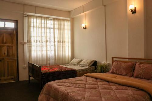a hotel room with two beds and a window at Vilasa Homestay in Darjeeling