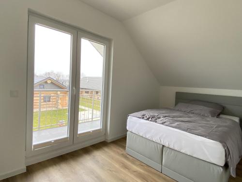 a bedroom with a bed and a large window at Seeglück 2 am Tollensesee in Groß Nemerow