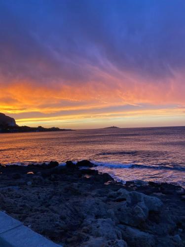 a sunset over the ocean with a rocky beach at Casa Repasi in Sferracavallo