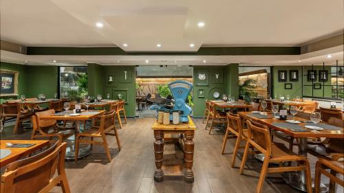 a restaurant with wooden tables and chairs and green walls at Rugendas Hotel Boutique by Time in Santiago