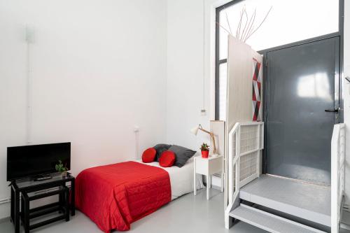 My City Home - Acogedora vivienda cerca de Pueblo Nuevo في مدريد: غرفة نوم بسرير احمر وتلفزيون
