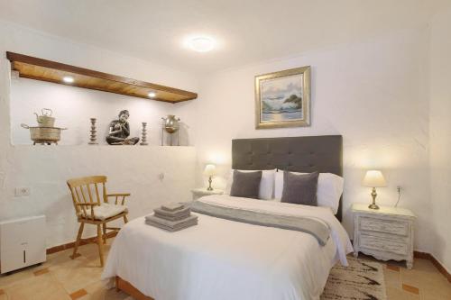 um quarto com uma grande cama branca e uma cadeira em Casa Karma em Arico