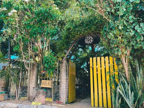琵琶的住宿－SAMO Hostel，一座树木繁茂的建筑前的黄色门