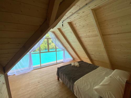 Riverside Komani Lake في Koman: غرفة نوم بسرير ونافذة كبيرة