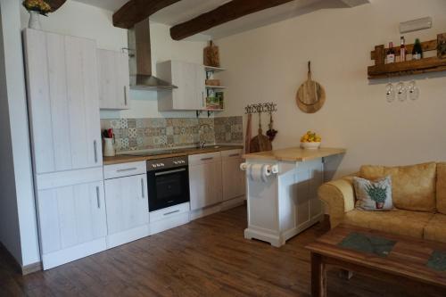een keuken met witte kasten en een bank in een kamer bij Casa Selvaggia in Badolato