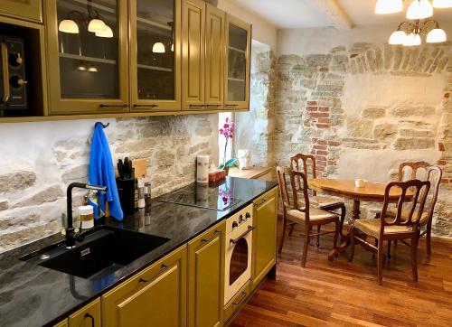 cocina con mesa y pared de piedra en Kohtu Apartment Cozy en Kuressaare