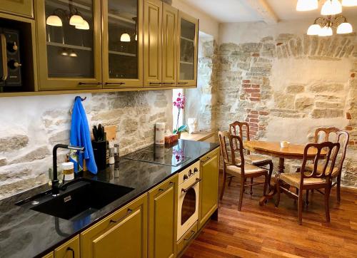 a kitchen with a table and a stone wall at Kohtu Apartment Cozy in Kuressaare