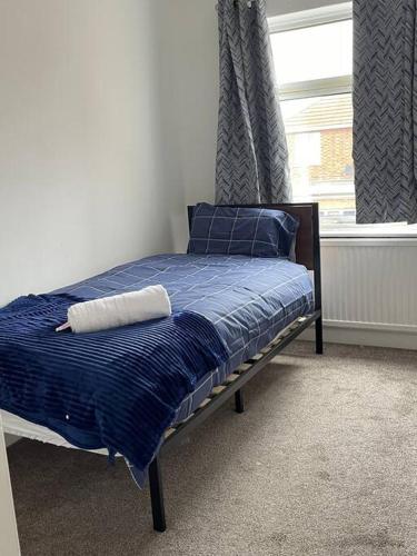 a bedroom with a bed with blue sheets and a window at Ideal Location for Work/Fun/Food/Holidays/Gym in Peterborough