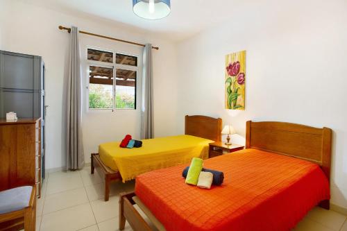 2 camas en una habitación de color amarillo y naranja en Cantinho Solpraia, en Porto Santo