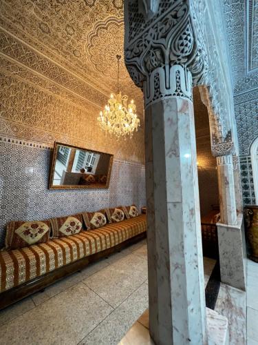 een woonkamer met een bank en een kroonluchter bij Riad Del Rey in Rabat
