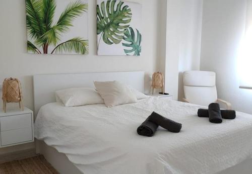 ein weißes Bett mit zwei schwarzen Hausschuhen drauf in der Unterkunft Alonis Suites Premium Villas Onaer in Callosa d'en Sarrià
