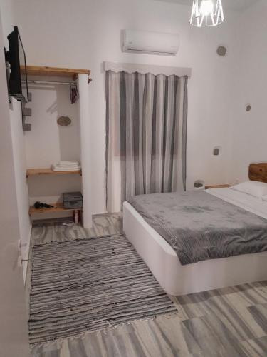 um quarto com uma cama com uma cortina e uma televisão em George's Home Platy Gyalos em Kalymnos
