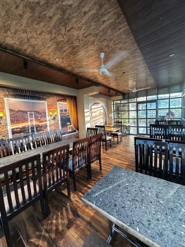 a dining room with wooden tables and chairs and windows at HOTEL ROYAL SUITES + in Ajmer