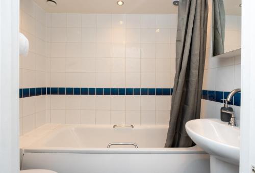 a bathroom with a bath tub and a sink at Free Parking Coastal Modern One Bedroom Apartment in Great Yarmouth