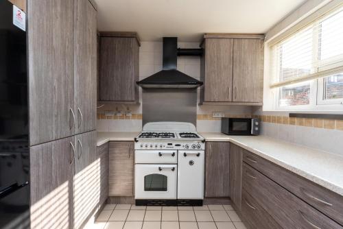 a kitchen with a white stove and wooden cabinets at Free Parking Coastal Modern One Bedroom Apartment in Great Yarmouth