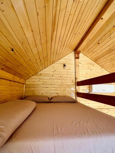 a bed in a room with a wooden ceiling at Cabana Bahna 2 in Orşova