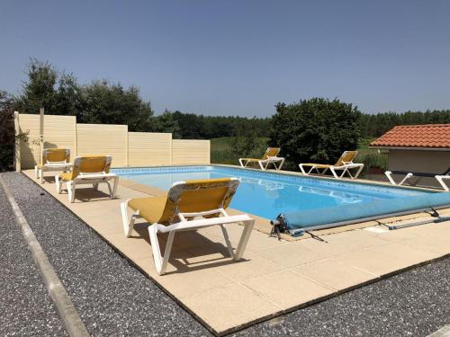 a swimming pool with chairs and a dog sitting next to it at Garrelon in Mont-de-Marsan