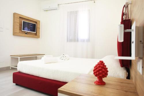 a bedroom with a bed with a red vase on a table at Gli Archi garden rooms in Favignana