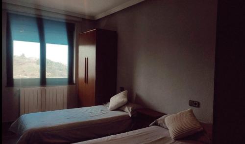 1 dormitorio con 2 camas y ventana en CASA FREDO, en Cóbreces