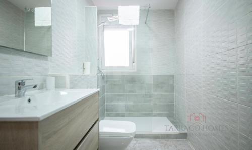 Baño blanco con aseo y lavamanos en TarracoHomes, TH134 Apartamento Llorer, en Tarragona