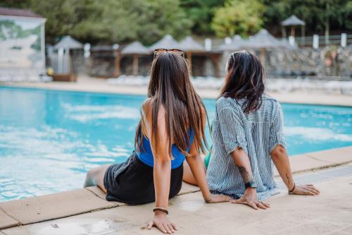 2 femmes assises à côté d'une piscine dans l'établissement Camping la Clémentine, à Cendras
