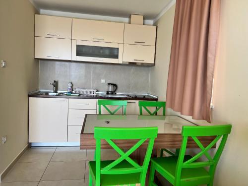 cocina con mesa y 2 sillas verdes en Villa Gradina, en Baška Voda