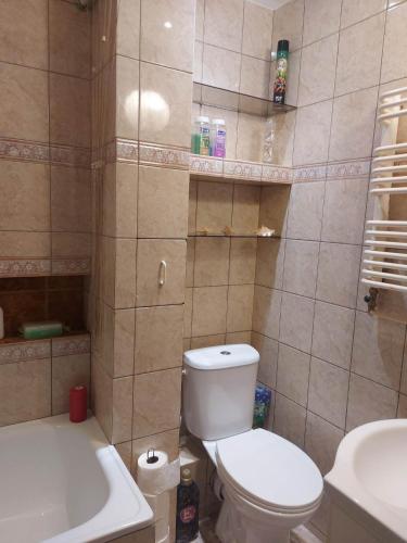 a bathroom with a toilet and a sink and a tub at Mieszkanie do wynajęcia w Centrum in Olecko