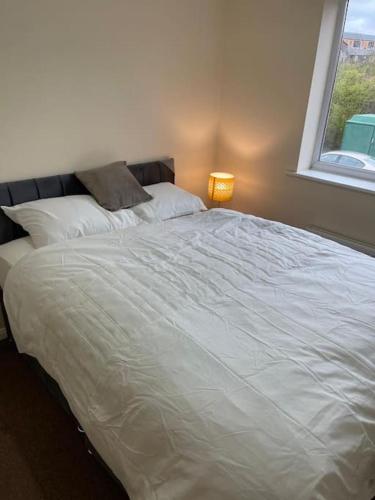 a large white bed in a bedroom with a window at Ideal Flat for Work/Holidays/Fun in Etruria